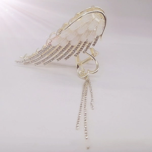 Close-up of golden angel wing hair claw clip with rhinestones and tassel chains
