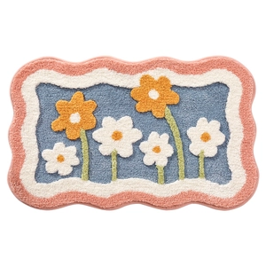 Floral bath mat with orange blossoms and green leaves on a blue water-absorbent rug