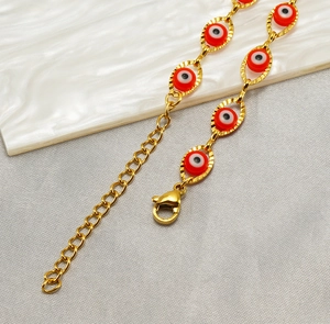 Detailed close-up of golden stainless steel evil eye bracelet with red glass beads
