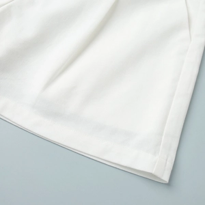 Detailed view of the flat hem stitching on a white vest and shorts cotton blend set