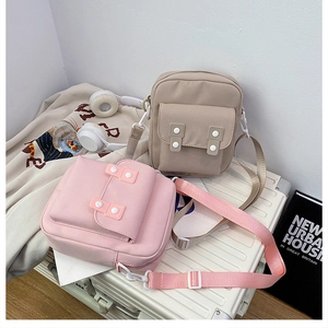 Detail of pink and khaki canvas crossbody bags on luggage for casual city travel