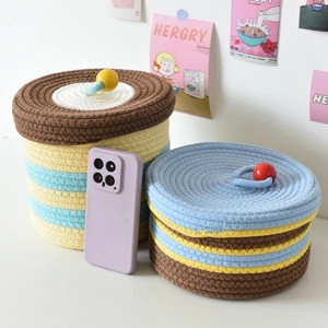 Close-up of small and large cotton rope woven storage baskets with colorful pom-pom lids