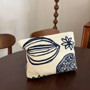 Off-white canvas cosmetic bag with dark blue floral print on vintage wooden table