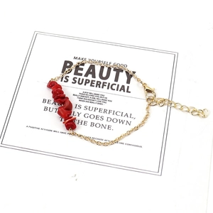 Macro detail of irregular red stone beads and adjustable gold chain with lobster clasp
