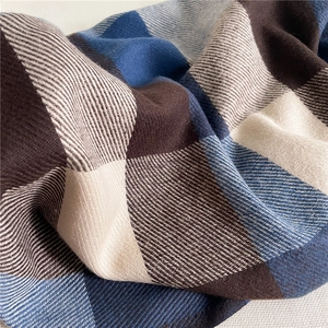 Detailed macro view showing the thick twill weave texture of the plaid tassel scarf