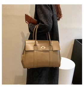 Detail of vintage camel leather tote bag with gold twist-lock and textured finish