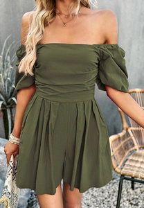 Olive green off-shoulder romper with ruffled bodice and pleated shorts in garden setting