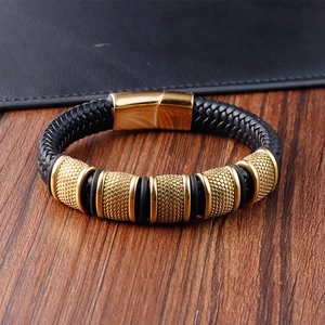 Detail of men's black braided leather bracelet with golden magnetic clasp and textured rings