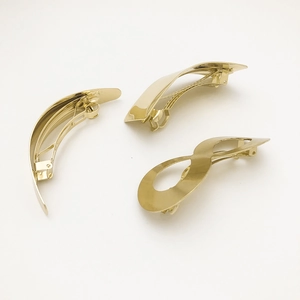 Detailed view of three minimalist gold metal hair clips in moon and infinity shapes