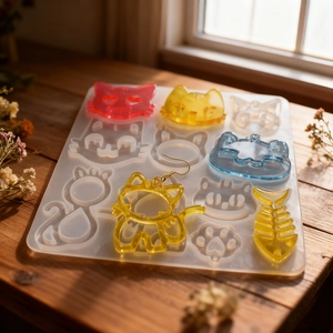Detailed view of translucent cat silicone molds and colorful resin earrings on wood