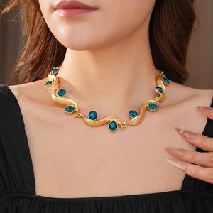 Macro view of vintage gold wavy necklace with inlaid blue round gemstone for women