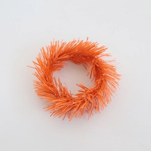 Detailed view of an orange textured PVC wreath candle ring with festive pine needle fibers