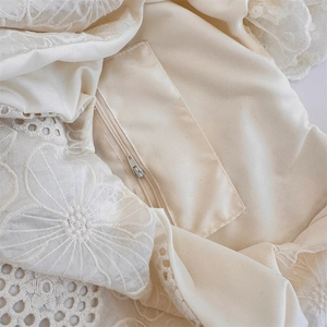 Detail shot of cream canvas tote featuring delicate floral embroidery and zipper closure