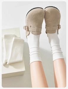 Detail of white ribbed cotton mid-calf socks paired with beige suede buckle mules