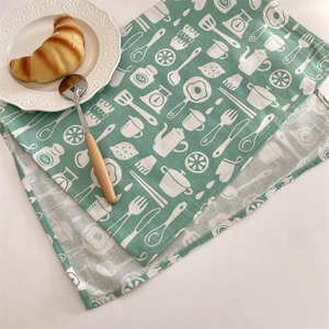 Détail de la serviette en lin vert menthe avec motifs de cuisine et croissant sur l'assiette
