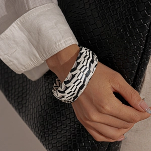 Detail of a wide zebra-patterned cuff bracelet featuring black and white geometric panels
