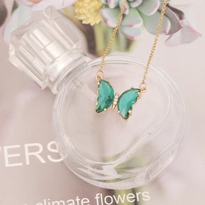 Elegant gold butterfly necklace with green translucent wings and sparkling white crystals