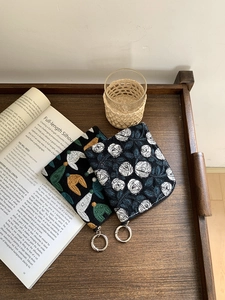 Detail of embroidered linen pouches with floral and hat patterns on a wooden tray
