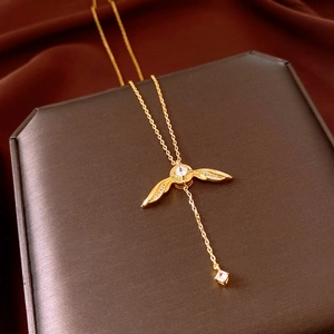 Détail d'un collier doré avec pendentif aile et zircons sur un écrin à bijoux