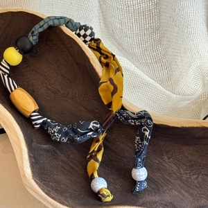 Detail of bohemian fabric printed beads and acrylic heart pendant on a wooden tray