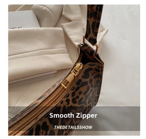 Detail of smooth golden zipper and refined leopard print on a stylish shoulder bag