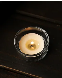 Primo piano di una candela accesa in un portacandele di vetro su sfondo di legno scuro