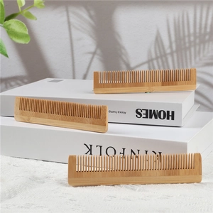 Three natural eco-friendly bamboo hair combs displayed on minimalist books in soft light