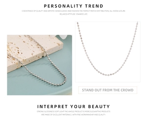 Polished silver bead chain necklace displayed on stone texture and white background