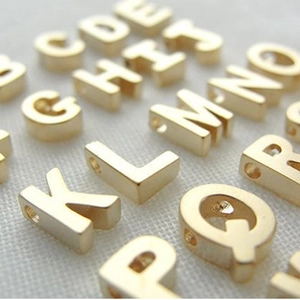 Macro shot of gold plated titanium steel alphabet charms with holes for DIY jewelry