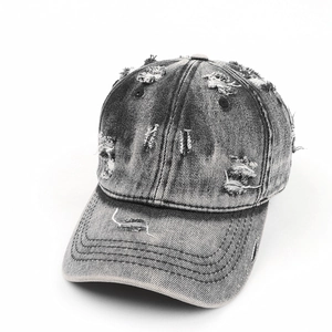 Close-up of distressed ripped details on vintage washed black denim baseball cap