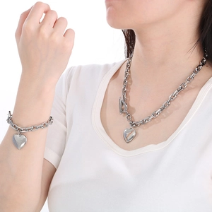 Close-up of chunky silver stainless steel necklace and bracelet set with heart pendants