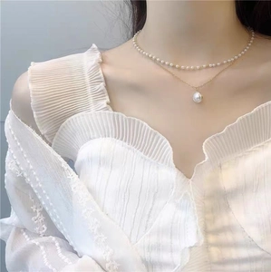 Elegant double layer necklace featuring gold chain with pearl pendant on model