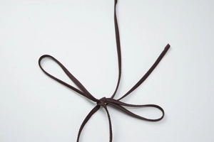 Detailed view of the brown fabric shoulder strap tied in a neat bow on the bikini top