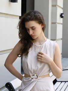 Détail d'un collier à pampilles en or 18 carats avec perles sur une robe beige chic