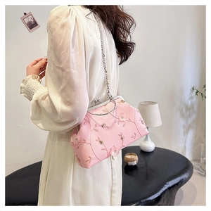 Detail of pink floral embroidered evening bag with silver handle and chain on model