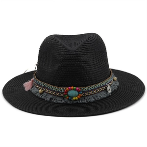Detail view of a black straw hat featuring bohemian tassels and turquoise embellishments