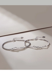 Detail view of silver couple bracelets with elegant branch and bamboo designs on beige surface