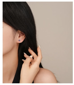Detailed view of 925 silver flower stud earring with blue zircon petals on model ear