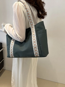 Dettaglio della grande borsa tote verde scuro con tracolla a motivi e tasca esterna