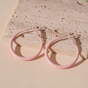 Detail shot of pink pastel hoop earrings on a minimalist stone texture base