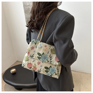 Detail of floral tapestry chain bag worn by a model in a minimalist modern setting