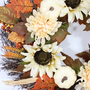 Autumn wreath with white sunflowers, pumpkins, and maple leaves on a vine base