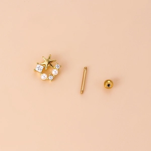 Golden star stud earrings with pearls and gemstones on a soft pink background
