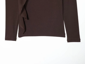 Detailed close-up of dark brown long sleeve top hem with delicate ruffled side design