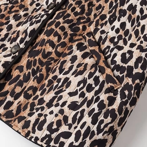 Detailed close-up of leopard print quilted jacket with black buttons and pocket stitching