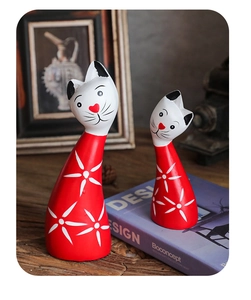 Close-up of red and white wooden cat figurines with floral patterns and heart-shaped nose