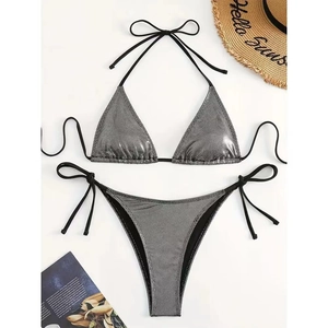 Vista piatta di un bikini metallizzato argento con lacci neri e accessori da spiaggia