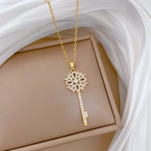Close-up of gold titanium steel key necklace with sparkling flower shaped zircon pendant