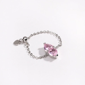 Detail of adjustable silver chain ring with two pink pear-shaped stones and heart charm