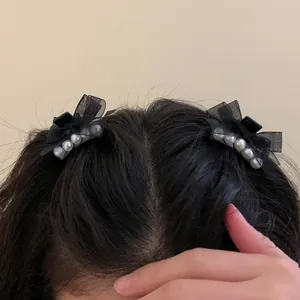 Detail of elegant black tulle bow hair clips with pearls shown on long black hair